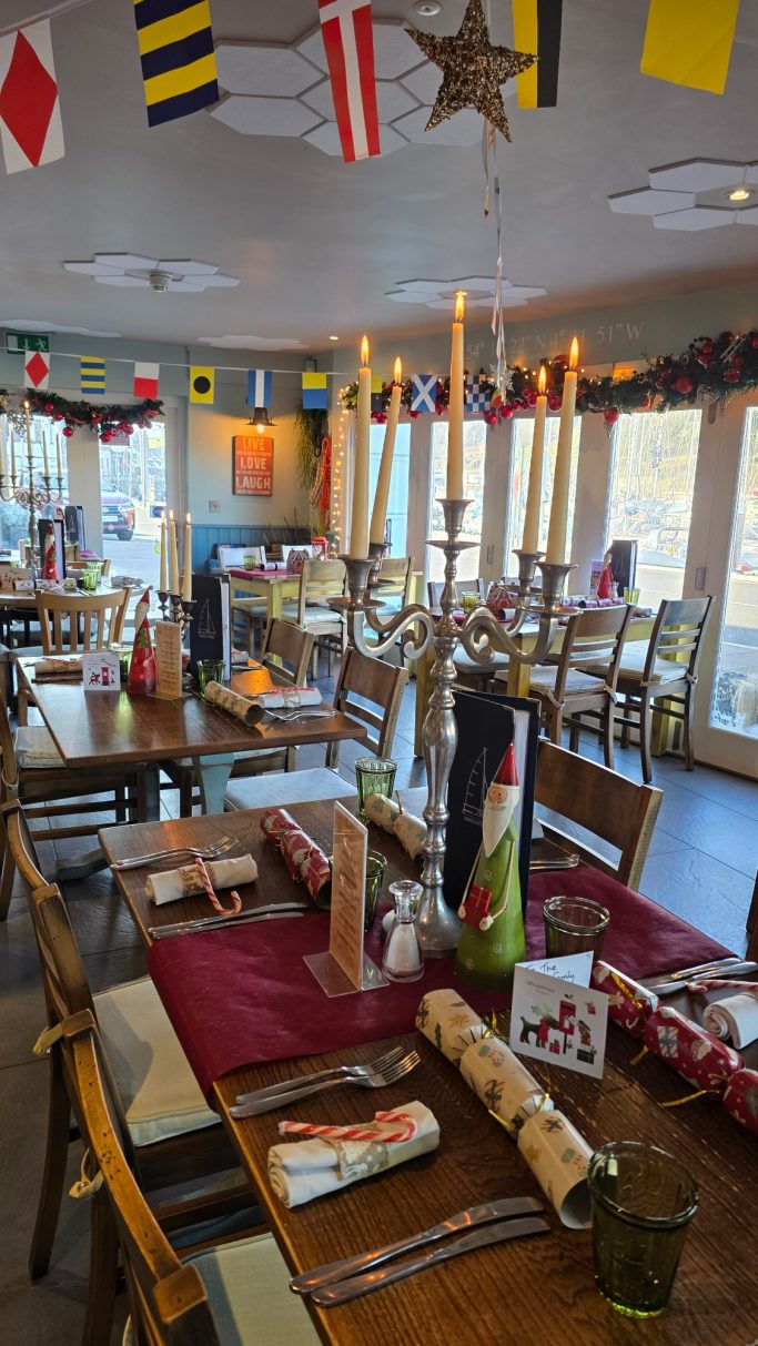 Decorated restaurant interior with festive tables and candles set for a gathering.