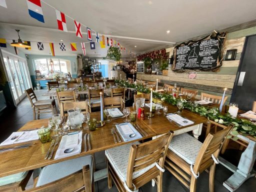 A cozy dining area with tables set for a meal, adorned with flags and greenery.