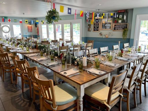 A decorated dining room set for a large gathering with greenery and colourful flags.